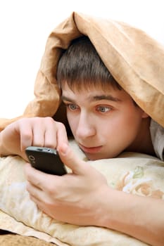 Teenager with Cellphone under Blanket at the Home