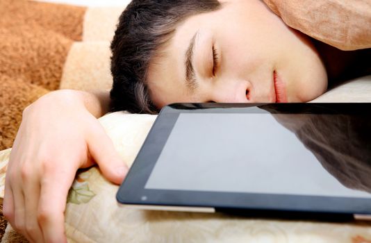 Tired Teenager sleeping at the Home with Tablet Computer