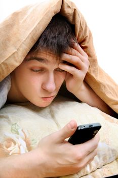 Thoughtful Teenager with Cellphone under Blanket at the Home