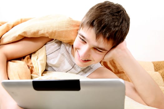 Cheerful Teenager with Tablet Computer in the Bed at the Home
