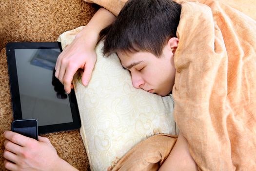 Tired Teenager sleeping at the Home with Tablet Computer