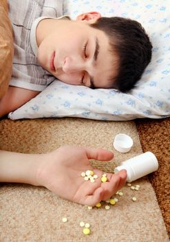 Teenager sleeps near the scattered Pills on the Bed at the Home