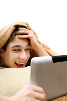 Cheerful Teenager with Tablet Computer under Blanket at the Home