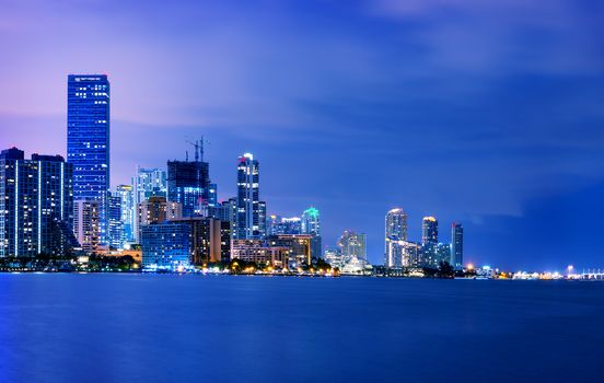 Miami city skyline panorama at dusk with urban skyscrapers over sea with reflection 