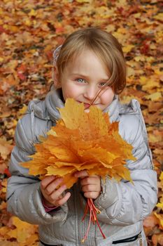 sympathetic little girl plays with leaves in the park