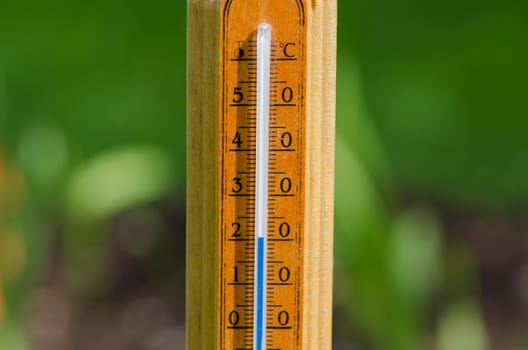 wooden outdoor thermometer shows 20 degrees celsius on nature background