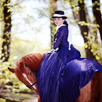 Lady on a  horse. The lady on riding walk. Portrait of the horsewoman. The woman astride a horse. The aristocrat on riding walk.