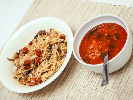 Rice with pasta and a bowl of tomato soup on a cotton piece