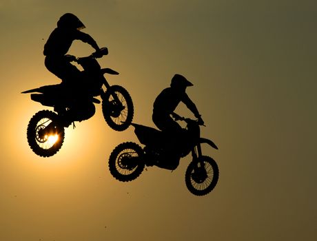 Motorcycle jumps in the air with sunset