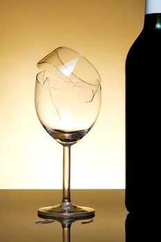 Vine bottle and broken glass on orange background
