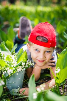 Spring in the forest. A cute boy with lilies of the valley