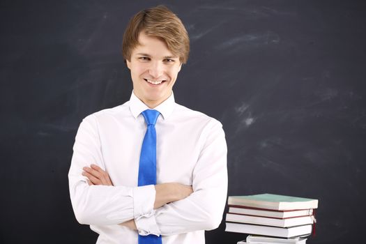 Portrait of a young, handsome man standing against the background of blackboard