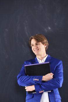 Portrait of a young, handsome man standing against the background of blackboard