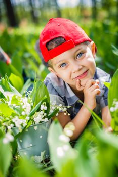 Spring in the forest. A cute boy with lilies of the valley