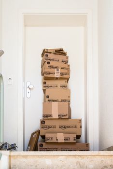 OSTFILDERN-SCHARNHAUSEN, GERMANY - MAY 18, 2014: A large stack of parcels by Amazon.com in different sizes is awaiting its customer in front of an entrance door of a flat on May, 18, 2014 in Ostfildern-Scharnhausen near Stuttgart, Germany. This conceptual photo can serve different purposes: It might demonstrate the domination of Amazon.com in the area of online shopping or the trend in general to shop online for all the different items you need in your personal life.