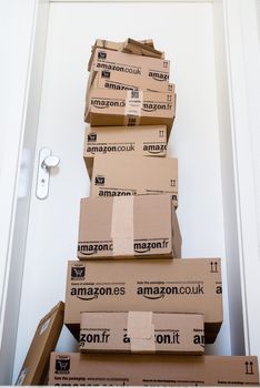 OSTFILDERN-SCHARNHAUSEN, GERMANY - MAY 18, 2014: A large stack of parcels by Amazon.com in different sizes is awaiting its customer in front of an entrance door of a flat on May, 18, 2014 in Ostfildern-Scharnhausen near Stuttgart, Germany. This conceptual photo can serve different purposes: It might demonstrate the domination of Amazon.com in the area of online shopping or the trend in general to shop online for all the different items you need in your personal life.