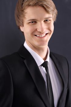 Portrait of a young, handsome man standing against the background of blackboard