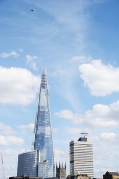 LONDON, UK - MAY 25, 2014: A British Airways aeroplane flies above The Shard skyscraper in London, UK on May 25, 2014. The cityscape includes The Place, the tower of Southwark Cathedral and Guy's Hospital.