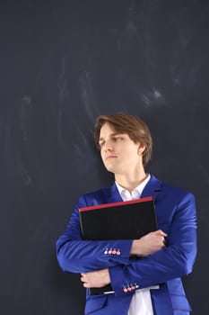 Portrait of a young, handsome man standing against the background of blackboard