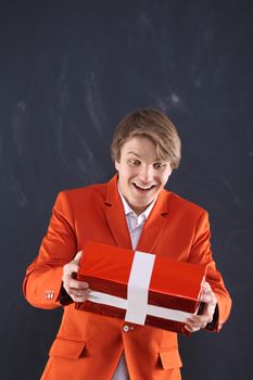 Portrait of a young, handsome man in the orange jacket standing on black background