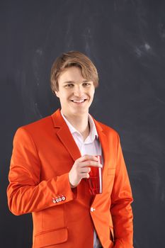 Portrait of a young, handsome man in the orange jacket standing on black background plate