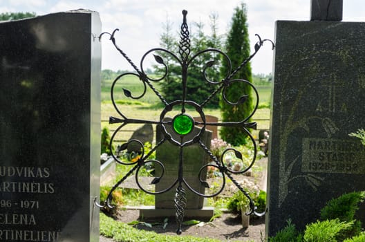 brass black star shaped ornament with shiny green stone in the cemetery