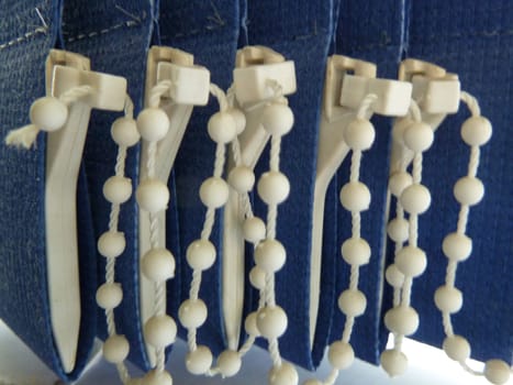 White plastic beaded chain on blue vertical blinds