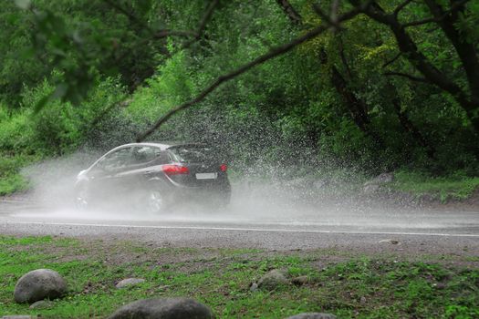 Automobile driving on the puddle on a highway