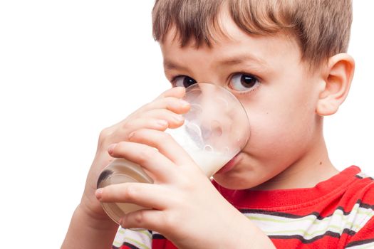Young boy drinking milk out of glass on white background