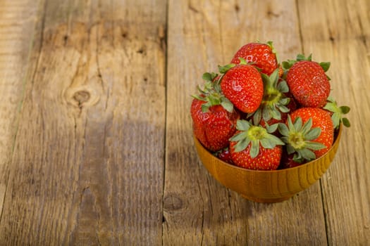 fresh strawberries in wood bowl on old wooden background