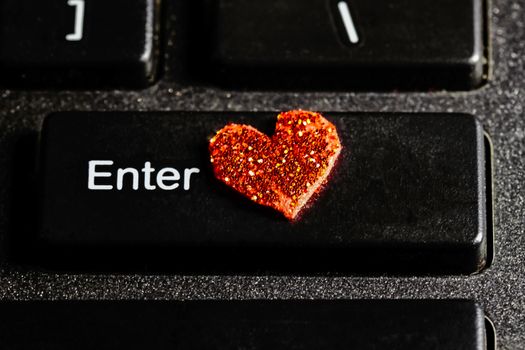 Closeup of computer keyboard showing the 'Enter' key with a red shiny heart symbol beside  the word