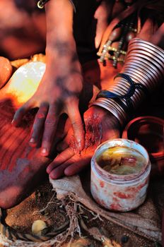 Himba woman mixing red ochre with petroleum jelly to apply to body. Traditionally it was mixed with animal fat.
