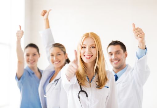 attractive female doctor with group of doctors showing thumbs up