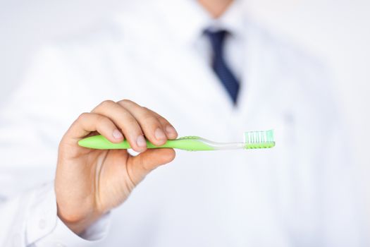 close up of male dentist or stomatologist holding toothbrush..