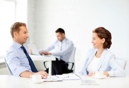 smiling businesswoman and businessman discussing something in office