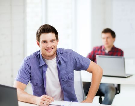 education - group of smiling students with laptops at school