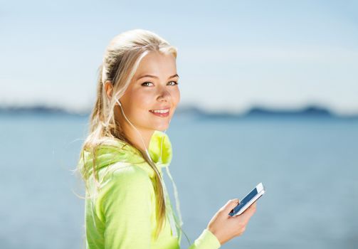 fitness and lifestyle concept - woman doing sports and listening to music outdoors