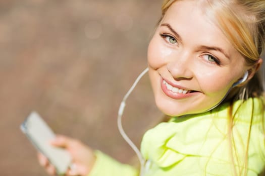 fitness and lifestyle concept - woman doing sports and listening to music outdoors