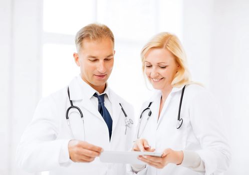 healthcare and technology concept - two doctors looking at tablet pc
