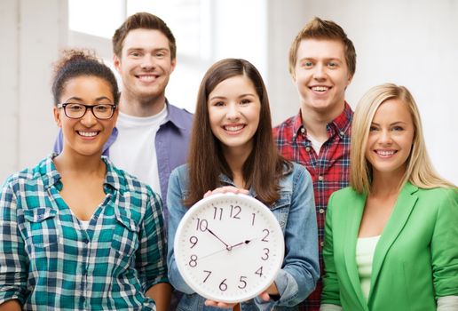 education concept - group of students at school with clock