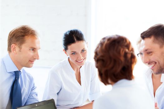 smiling businesswoman with team on meeting in office