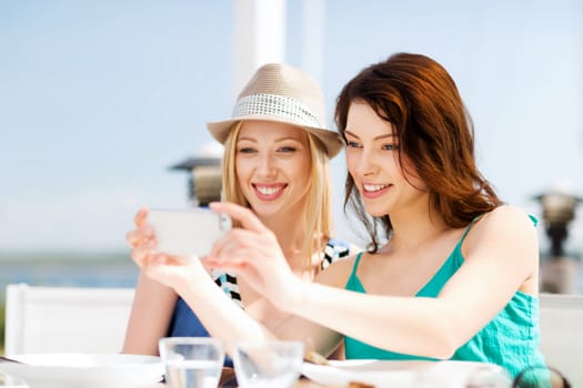 summer holidays and vacation - girls taking photo in cafe on the beach