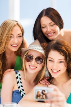 summer holidays and vacation - girls taking photo in cafe on the beach