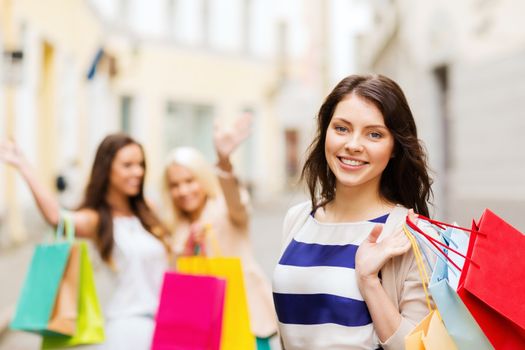 shopping and tourism concept - beautiful girls with shopping bags in ctiy