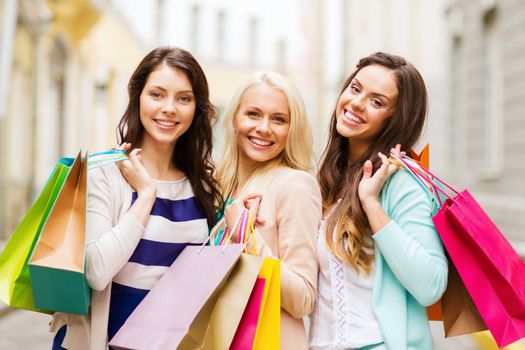 shopping and tourism concept - beautiful girls with shopping bags in ctiy