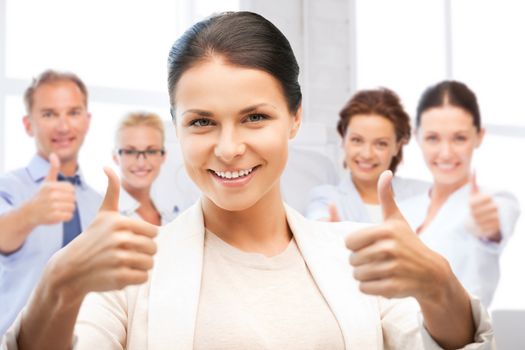 business and success - happy businesswoman showing thumbs up in office