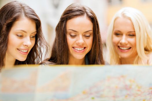 holidays and tourism concept - beautiful girls looking into tourist map in the city