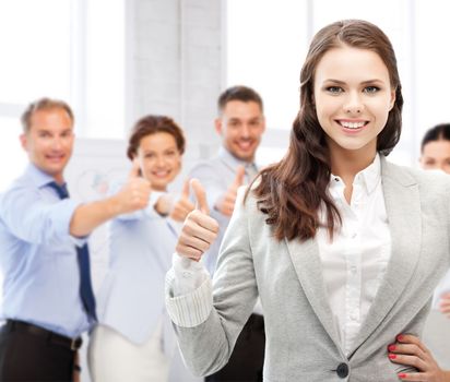 business and success - happy businesswoman showing thumbs up in office