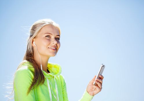 sport and lifestyle concept - woman doing sports and listening to music outdoors