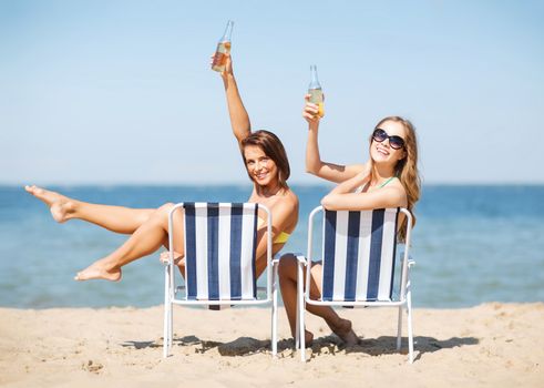 summer holidays and vacation - girls sunbathing and drinking on the beach chairs